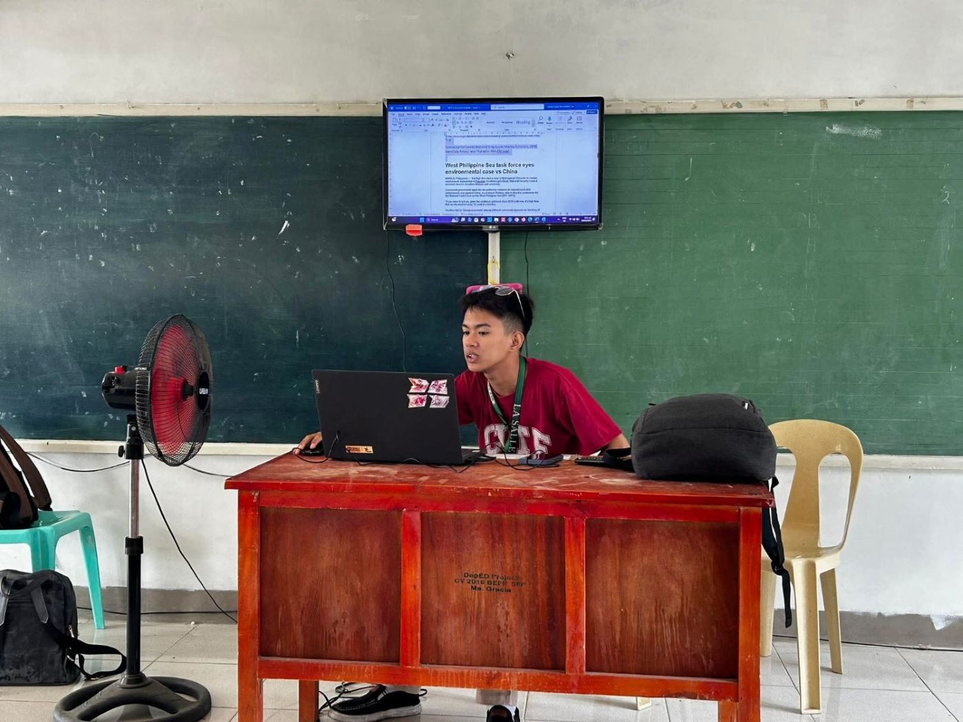 Moises teaching a computer basics lesson from a laptop connected to the classroom TV